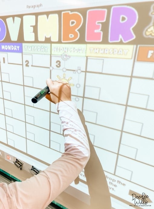 student writes on the interactive whiteboard calendar