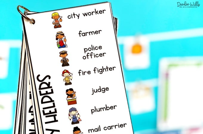 Writing center vocabulary words on a binder ring. Class activities schedule showing illustrated icons for story time, math, lunch, art, circle time, music, science, and calendar.