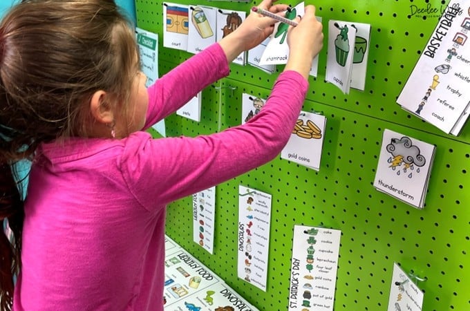 Student places illustrated vocabulary cards on a green pegboard, organizing picture-word cards during a classroom literacy activity.